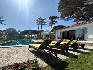a group of lounge chairs next to a swimming pool at Solar Do Magoito in Sintra