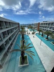 a hotel with a pool with a palm tree in the middle at Gav 2 Life in Ipojuca