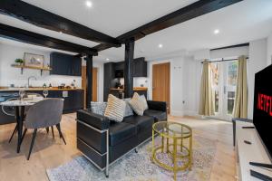 a living room with a black couch and a kitchen at Modern & Historic Mill Flat with Stream Views in Godalming