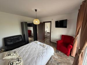a bedroom with a bed and a red chair at Vila Dinka in Lipovac
