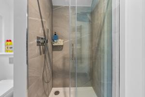 a shower with a glass door in a bathroom at Modern & Historic Mill Flat with Stream Views in Godalming +22 photos