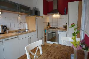 ボーデンヴェルダーにあるDas Fischerhausの白いキャビネットと木製テーブル付きのキッチン