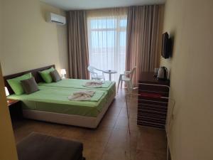 a bedroom with a bed and a table and a window at Амон Ра 2 in Primorsko