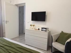a bedroom with a tv and a dresser with a chair at Room 28 in Conversano