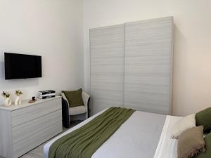 a bedroom with a bed and a tv and a chair at Room 28 in Conversano