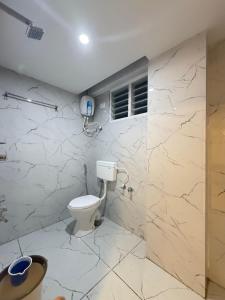 a bathroom with a toilet and marble walls at hotel ak grand in Mangalore