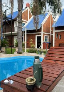 a green thermos sitting on a wooden table next to a swimming pool at El Sitio Azul Cabañas in Esquina