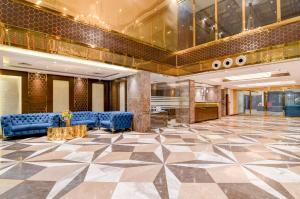 a lobby with blue chairs and a checkerboard floor at Kzar Central in Kolkata