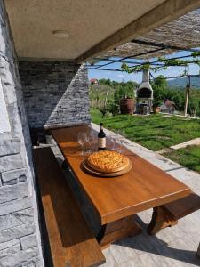 a pizza sitting on a wooden table on a patio at Vineyard Cottage with Private Jacuzzi in Metlika