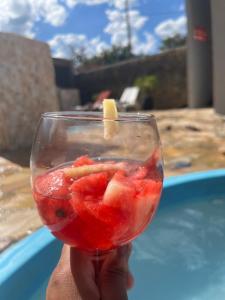 a person holding a glass with fruit in it at Chácara sonho meu in Jacutinga