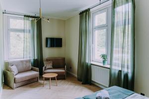 a bedroom with a couch and a chair and windows at Sztuka Gór in Nowa Ruda