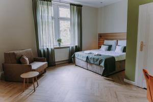a bedroom with a bed and a chair and a window at Sztuka Gór in Nowa Ruda