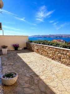 a patio with a stone wall and a stone flower pot at Villa Annabella Beach Apartments - 100m from Sea in Cesarica