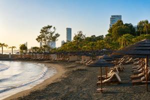 a beach with chairs and umbrellas and the ocean at Maison Amalthea in Limassol +4 photos