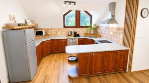 a kitchen with wooden cabinets and a white refrigerator at Apartmán pod Skalou in Vysoká nad Kysucou