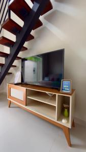 a living room with a tv on a cabinet and a staircase at Loft Duplex Moderno - 50m da Praia - Ar - Wi-Fi in Salinas da Margarida