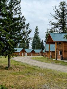 a row of wooden cabins with a tree and a road at NV Mountainview Chalets & RV Resort in McBride