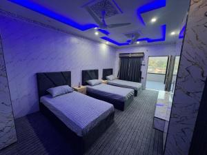two beds in a room with purple lights at Ajk bed & Breakfast in Gura Gujarān