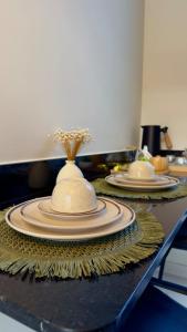 a table with two plates and a vase on it at Loft Duplex Moderno - 50m da Praia - Ar - Wi-Fi in Salinas da Margarida +16 photos