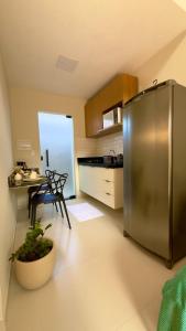a kitchen with a stainless steel refrigerator and a table at Loft Duplex Moderno - 50m da Praia - Ar - Wi-Fi in Salinas da Margarida
