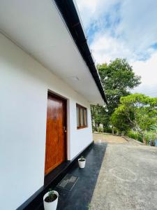 a house with a wooden door and two potted plants at Mountain Lodge Ella in Bandarawela +9 photos