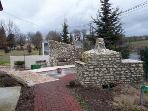 a stone house with a stone wall in a yard at Le Petit Breuil in Verteillac
