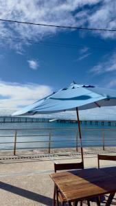 a wooden table with an umbrella on the beach at Loft Duplex Moderno - 50m da Praia - Ar - Wi-Fi in Salinas da Margarida
