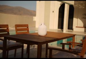 a white vase sitting on top of a wooden table at Cliff Chalet-Amrat in Al Amarat