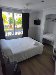 a bedroom with a bed and a television and a window at Hostal Cafetería La Rotonda in Ourense +12 photos