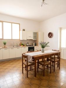 a kitchen with a wooden table and chairs and a kitchen with white cabinets at Casa dei mille in Castelsardo