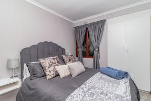 a bedroom with a large gray bed with pillows at Ruby on Hamilton in Windsor Park