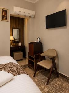 a hotel room with a chair and a desk and a television at Casa Latina pyramids view in Cairo
