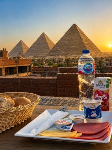 a plate of food with a bottle of water and the pyramids at Casa Latina pyramids view in Cairo
