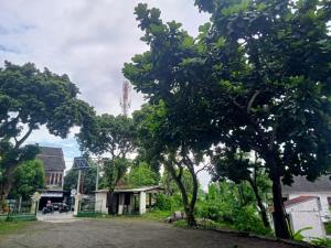 Eine Gruppe von Bäumen und Häusern mit einem Turm im Hintergrund in der Unterkunft Hotel Brawijaya in Timuran