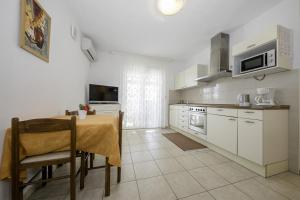 a kitchen with a table and a kitchen with white cabinets at Apartmani Leovac in Lopar