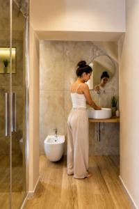 a woman standing in front of a sink in a bathroom at Almantra Rooms - Valle dei Templi e Mare in Favara