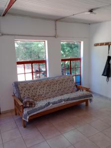 a couch sitting in a room with two windows at La casita de Gorrión in Villa Ventana