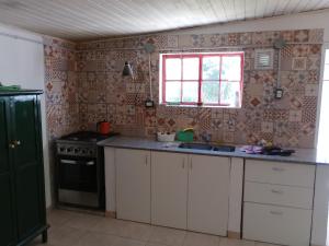 a kitchen with a sink and a stove and a window at La casita de Gorrión in Villa Ventana