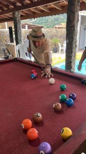 a man is playing pool on a pool table at Chácara sonho meu in Jacutinga