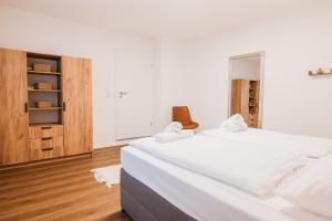 a white bedroom with a large bed and wooden floors at Waldblick am Ring in Kelberg