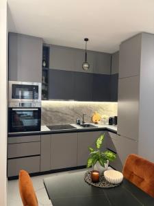 a kitchen with black and white cabinets and a table at Sarah Central City Apartment-Bar in Bar