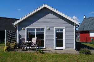 a small grey house with a table and chairs at Ferienhaus Heideblick in Zerpenschleuse