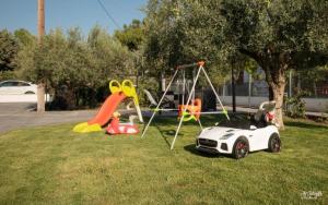 a playground with a toy car and a swing at Iraklia Coral in Nea Irakleia