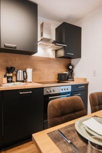a kitchen with black appliances and a wooden table at Waldblick am Ring in Kelberg