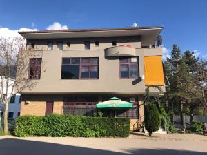 a house with a green umbrella in front of it at Bar Restaurant Hotel Drraska in Maliq