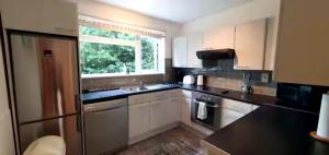 a kitchen with white cabinets and black counter tops at Reigate - 1 Bed by Mobius Property Solutions in Reigate