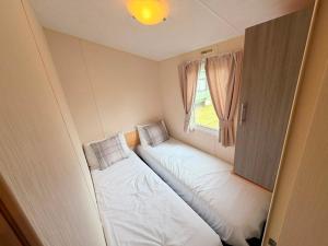 a small room with two beds and a window at Magnolia in Porthcawl