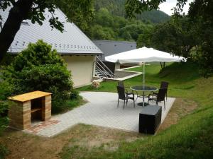 un patio con sombrilla, mesa y sillas en Hájovna Bukovec, en Bukovec