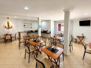 a dining room with wooden tables and chairs at BURITI HOTEL Barra do Riacho Aracruz in Aracruz