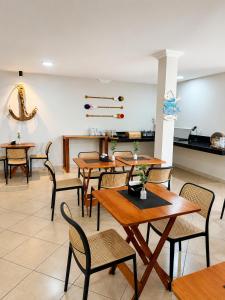 a dining room with wooden tables and chairs at BURITI HOTEL Barra do Riacho Aracruz in Aracruz